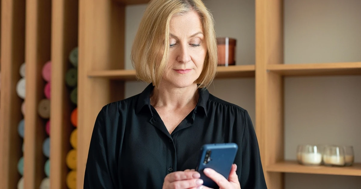 Zaakvoerster bekijkt een automatische afspraakherinnering op haar smartphone in haar zaak